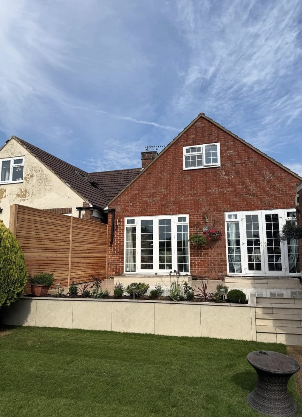 Slatted timber screen beside a house with a rendered raised planter and paved terrace